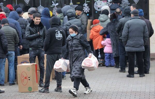 Женщина несет пакеты с хлебом мимо собравшихся возле магазина протестующих. - Sputnik Таджикистан