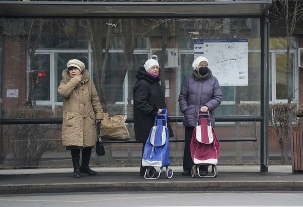 Женщины с напряженными лицами ждут транспорт на автобусной остановке в Алматы после протестов. - Sputnik Таджикистан