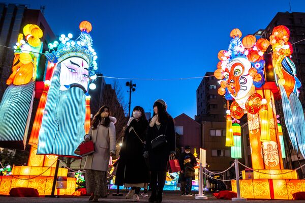 Люди проходят мимо праздничных фонарей в парке Ямаситачо в Иокогаме в преддверии китайского Нового года тигра по лунному календарю. - Sputnik Таджикистан