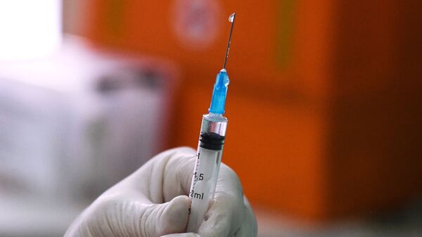 Медицинский сотрудник держит в руках шприц с вакциной от COVID-19 - Sputnik Тоҷикистон