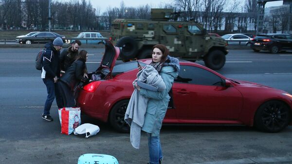 Люди складывают свои вещи в машину на одной из улиц в Киеве. - Sputnik Тоҷикистон