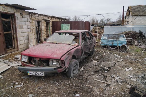 Разбитая машина и пострадавший во время обстрела дом в селе Гнутово под Мариуполем - Sputnik Таджикистан