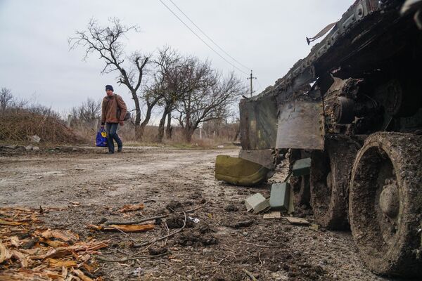 Житель села Гнутово идет мимо подбитого танка украинской армии под Мариуполем - Sputnik Таджикистан