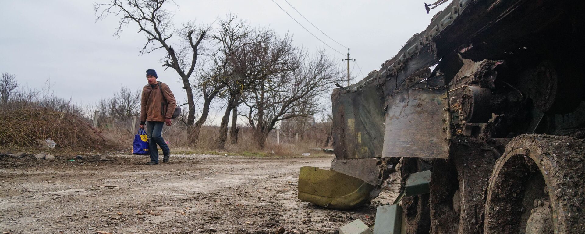 Житель села Гнутово идет мимо подбитого танка украинской армии под Мариуполем - Sputnik Тоҷикистон, 1920, 02.03.2022