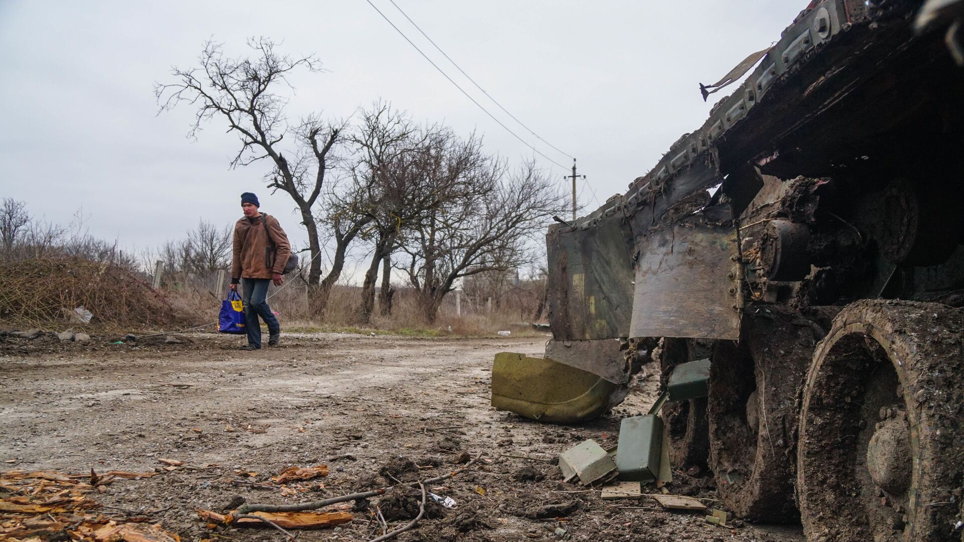 Житель села Гнутово идет мимо подбитого танка украинской армии под Мариуполем - Sputnik Таджикистан, 1920, 01.03.2022