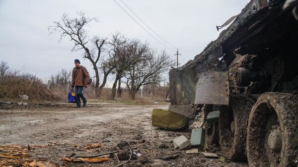 Житель села Гнутово идет мимо подбитого танка украинской армии под Мариуполем - Sputnik Тоҷикистон