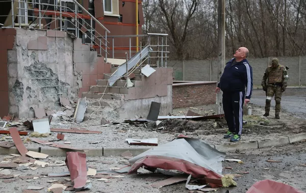 Житель города во дворе многоэтажного жилого дома в Донецке, поврежденного в результате обстрела