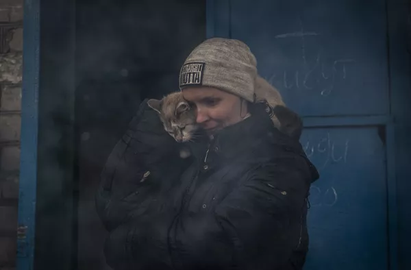 Женщина с кошкой у подъезда жилого дома в освобожденном городе Счастье в Луганской народной республике