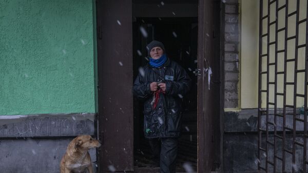 Женщина выходит из подъезда жилого дома в освобожденном городе Счастье в Луганской народной республике - Sputnik Тоҷикистон