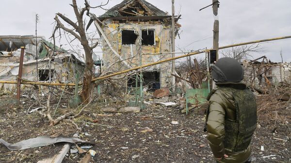 Мужчина фотографирует один из разрушенных домов села Сопино в Донецкой народной республике - Sputnik Таджикистан