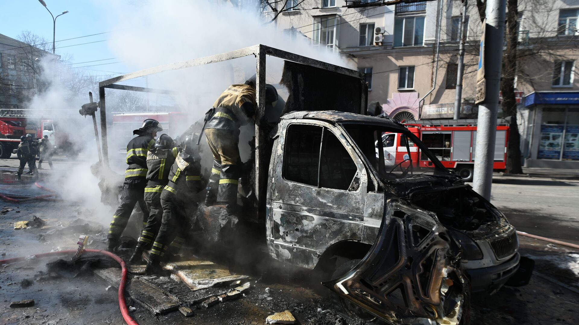Сотрудники пожарной охраны у разрушенной машины в результате взрыва в центре Донецка - Sputnik Таджикистан, 1920, 06.04.2022