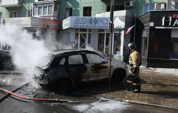 Пожарный пытается потушить машину, загоревшуюся после взрыва украинской ракеты.  - Sputnik Таджикистан