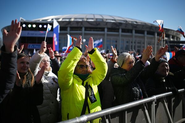 Люди смотрят трансляцию митинга-концерта, посвященного воссоединению Крыма с Россией, у большой спортивной арены Лужники в Москве - Sputnik Таджикистан