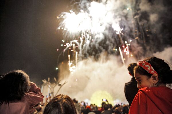 Люди смотрят, как фейерверк освещает небо, во время церемонии празднования Навруза в торговом центре Iran Mall в столице Ирана Тегеране.  - Sputnik Таджикистан