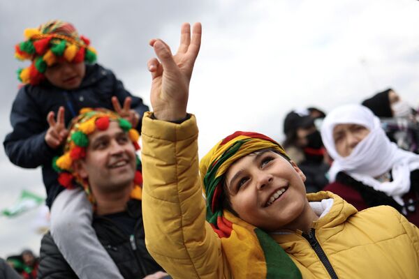 Люди поднимают пальцы в знак мира во время празднования Навруза, знаменующего приход весны, в Стамбуле. - Sputnik Таджикистан