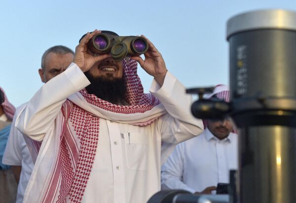 Житель Саудовской Аравии смотрит в бинокль на полумесяц, знаменующий начало священного для мусульман месяца Рамадан, в городе Таиф на юго-западе страны. - Sputnik Таджикистан