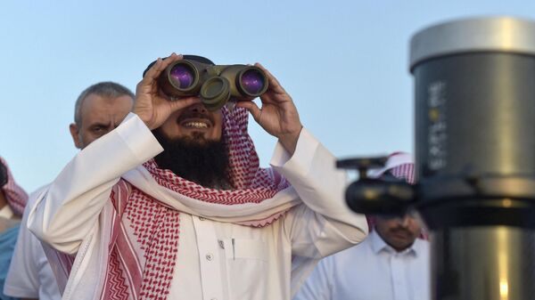 Житель Саудовской Аравии смотрит в бинокль на первый полумесяц, знаменующий начало священного для мусульман месяца Рамадан, в городе Таиф на юго-западе Саудовской Аравии - Sputnik Таджикистан