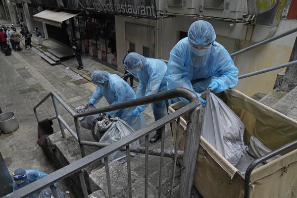 Работники отеля выбрасывают мусор возле изолированной гостиницы в Гонконге. - Sputnik Таджикистан