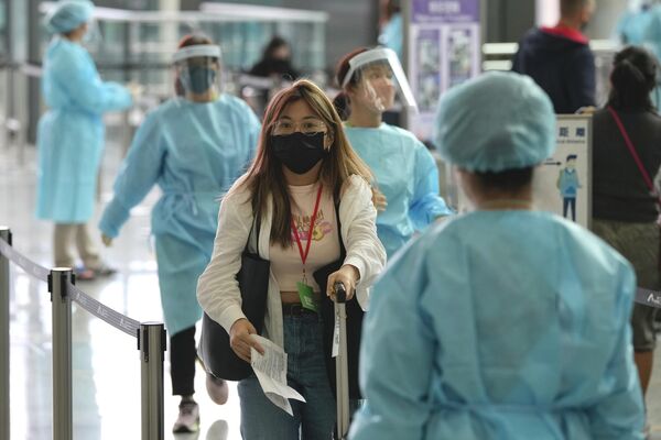Работники аэропорта Гонконга направляют пассажиров прибывающих рейсов в карантинные отели. - Sputnik Таджикистан