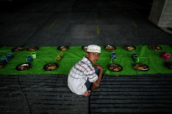 Верующий мусульманин сидит рядом с тарелками с едой в мечети Мьянмы. - Sputnik Таджикистан