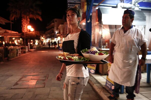 Официантка несет блюда возле ресторана на греческом острове Наксос в Эгейском море. - Sputnik Таджикистан