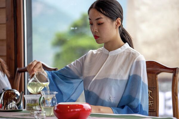 Женщина наливает китайский зеленый чай Синьян Маоцзянь. - Sputnik Таджикистан