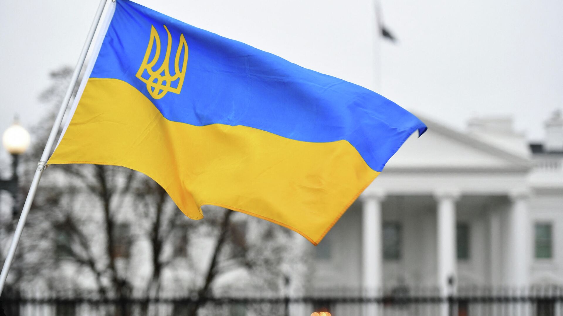 Флаг Украины с гербом развевается, когда активисты собираются на площади Лафайет в знак протеста против российского вторжения в Украину в Вашингтоне - Sputnik Таджикистан, 1920, 14.06.2022