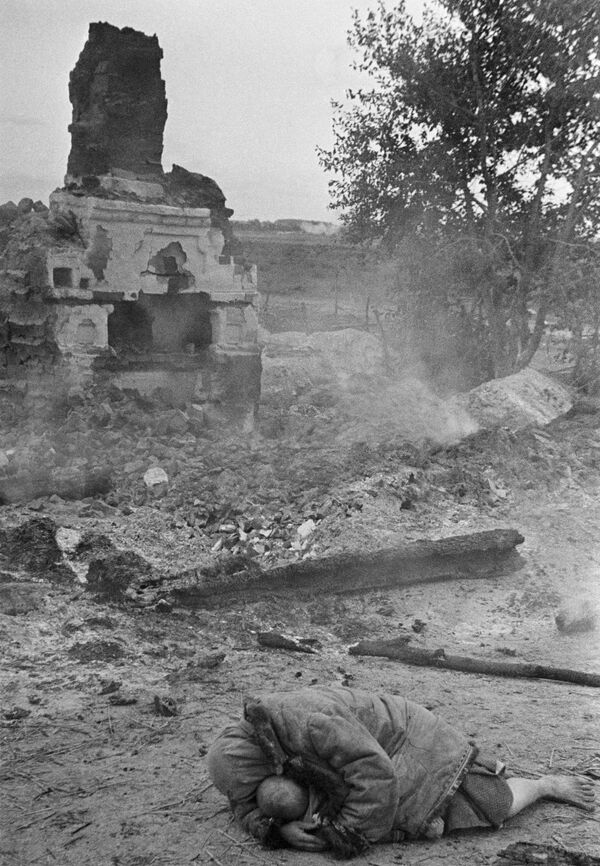 Мать укрывает своего ребенка во время обстрела. Деревня Красная Слобода, Брянский фронт, 1941 год. - Sputnik Таджикистан