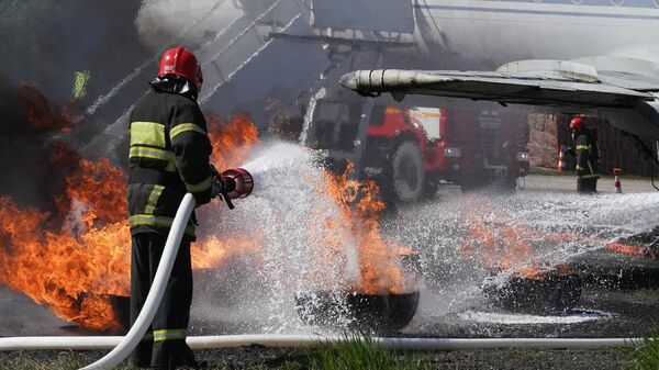 Пожарный тушит горящий самолет, архивное фото - Sputnik Таджикистан