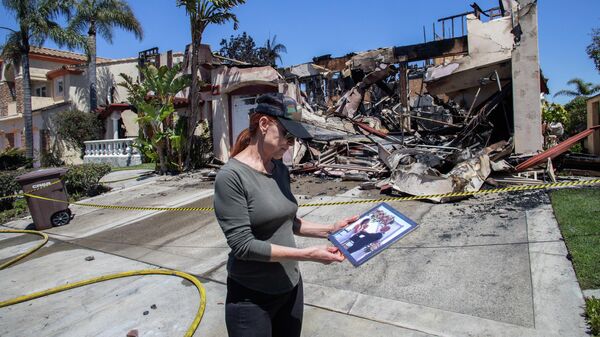 Женщина стоит перед своим сгоревшим домом в Лагуна-Нигел, США - Sputnik Тоҷикистон