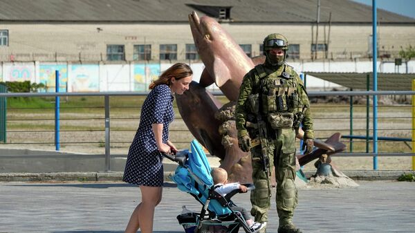 Женщина с коляской на набережной Херсона рядом с российским военным - Sputnik Таджикистан