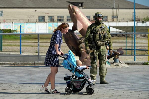 Женщина с коляской на набережной Херсона рядом с российским военным. - Sputnik Таджикистан