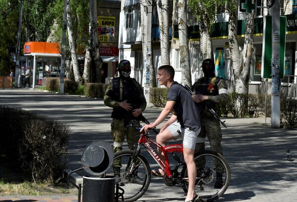 Велосипедист на фоне патрулирования украинского города Скадовск российскими военными. - Sputnik Таджикистан