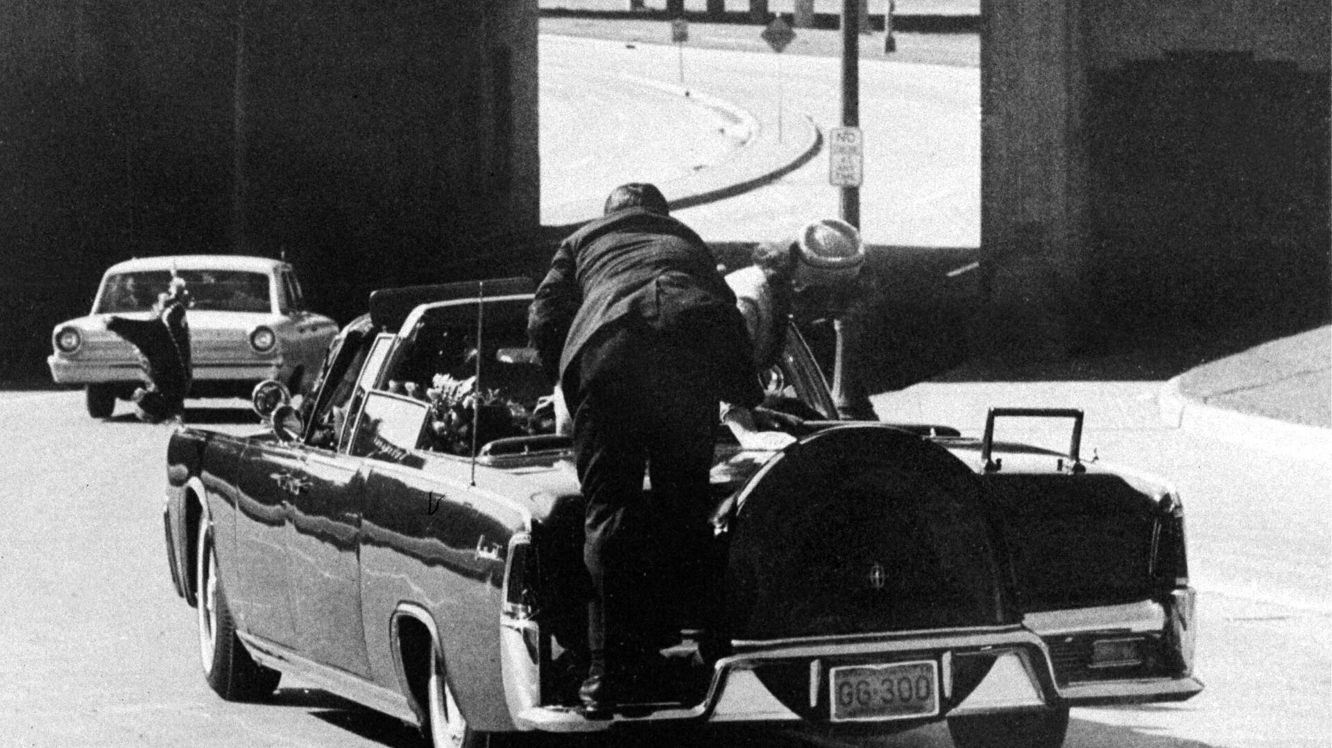 Президент Джон Ф. Кеннеди падает на заднее сиденье президентского лимузина, когда он мчится по улице Вязов к эстакаде Stemmons Freeway в Далласе после смертельного выстрела - Sputnik Таджикистан, 1920, 27.05.2022
