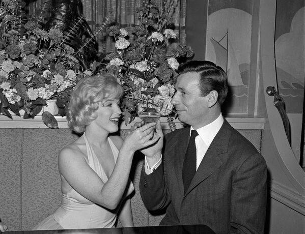 Мэрилин Монро и французский актер и певец Ив Монтан пьют шампанское 23 января 1960 года в ночном клубе в Голливуде. - Sputnik Таджикистан