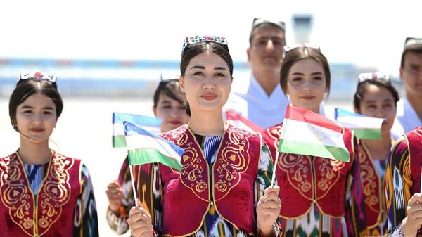 Узбекские девушки в национальных костюмах с флагами Узбекистана и Таджикистана - Sputnik Тоҷикистон