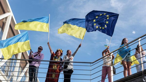 Люди машут украинскими национальными флагами во время демонстрации солидарности с Украиной на Кипре - Sputnik Таджикистан