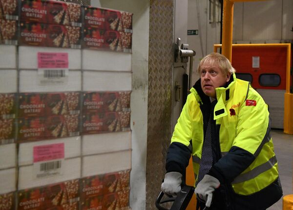 Премьер-министр Великобритании Борис Джонсон переносит поддон с шоколадным тортом в хранилище при температуре -25°C во время предвыборного визита в штаб-квартиру Iceland Foods в Дисайде, северо-восточный Уэльс, 8 ноября 2019 года.  - Sputnik Таджикистан