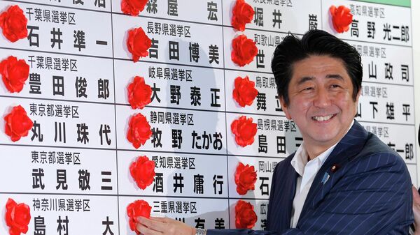 Премьер-министр Японии Синдзо Абэ ставит розетку на имя победившего кандидата от своей Либерально-демократической партии во время подсчета голосов на выборах в верхнюю палату парламента в штаб-квартире партии в Токио - Sputnik Таджикистан