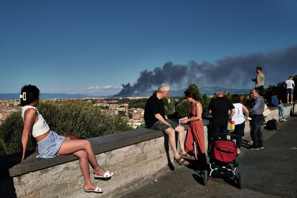 Люди на площади Гарибальди на холме Джаниколо смотрят на дым, поднимающийся после пожара возле археологического парка района Ченточелле в восточной части Рима. - Sputnik Таджикистан