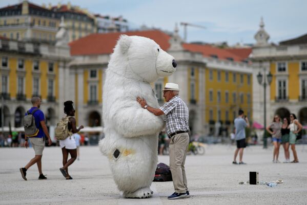 Мужчина разговаривает с человеком в костюме белого медведя на площади Комерсио в Лиссабоне, Португалия. - Sputnik Таджикистан