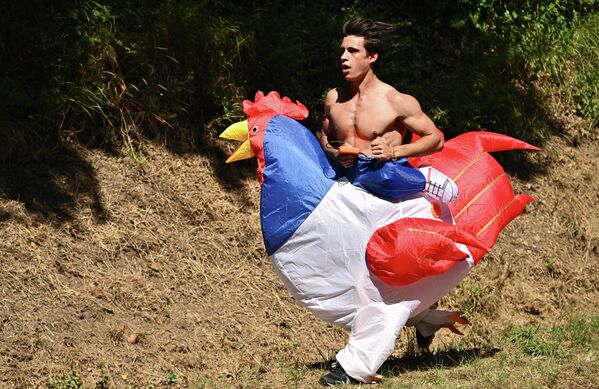 Зритель в костюме курицы бежит по обочине во время 15-го этапа 109-й велогонки Тур де Франс. - Sputnik Таджикистан