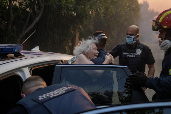 Пожарные и полицейские эвакуируют пожилую женщину из ее дома в Пентели в Греции. - Sputnik Таджикистан