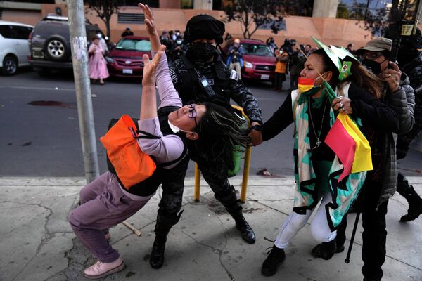 Полицейский пытается помешать антиправительственному демонстранту таскать за волосы женщину в Боливии. - Sputnik Таджикистан