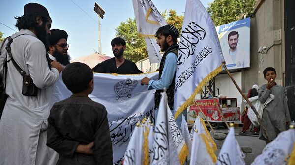 Мужчины покупают талибские  флаги на улице в Кабуле - Sputnik Таджикистан