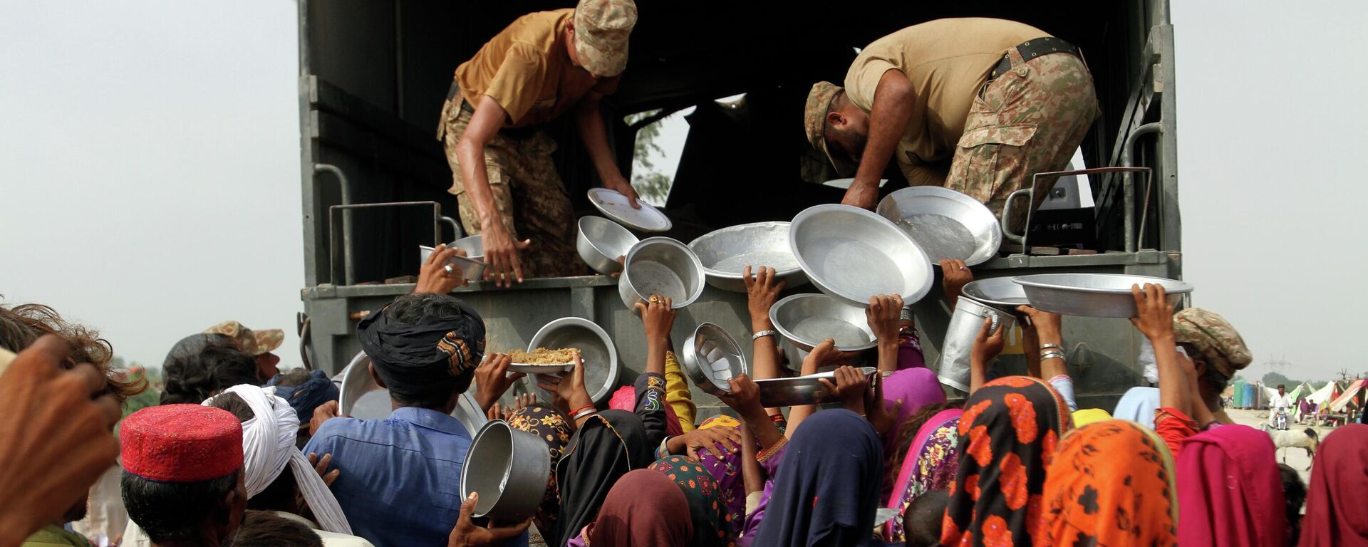 Люди получают еду во время наводнения в Пакистане  - Sputnik Тоҷикистон, 1920, 06.09.2022