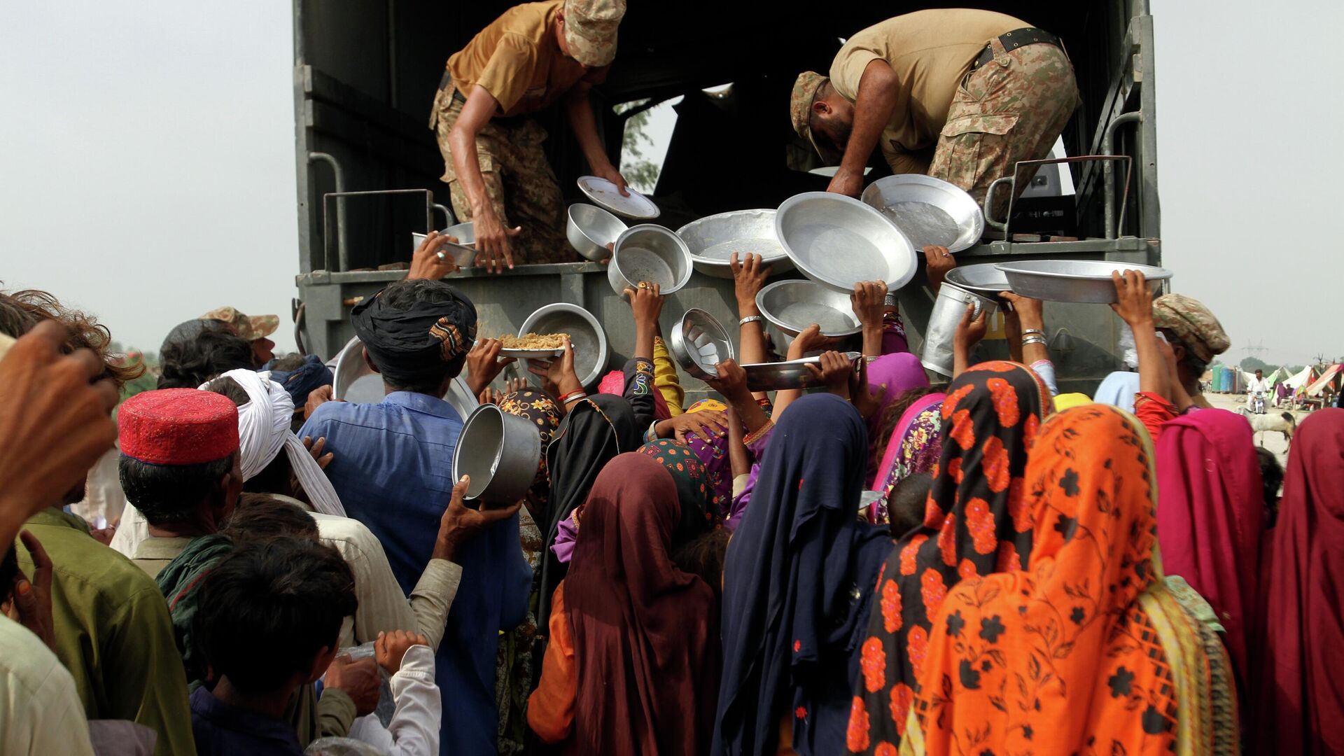 Люди получают еду во время наводнения в Пакистане  - Sputnik Тоҷикистон, 1920, 29.12.2022