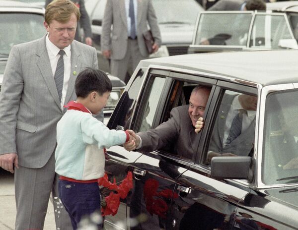 Горбачев приветствует китайского школьника из правительственного кортежа в Шанхае во время визита. - Sputnik Таджикистан