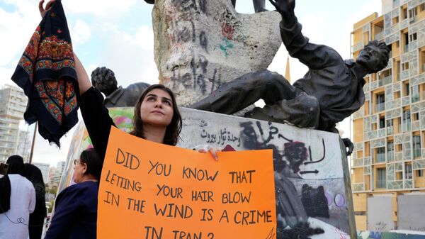 Лава Бейкер держит платок и плакат во время акции протеста в Бейруте, Ливан  - Sputnik Таджикистан