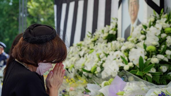 Женщина у портрета экс-премьера Японии Синдзо Абэ до начала государственных похорон в Токио  - Sputnik Таджикистан